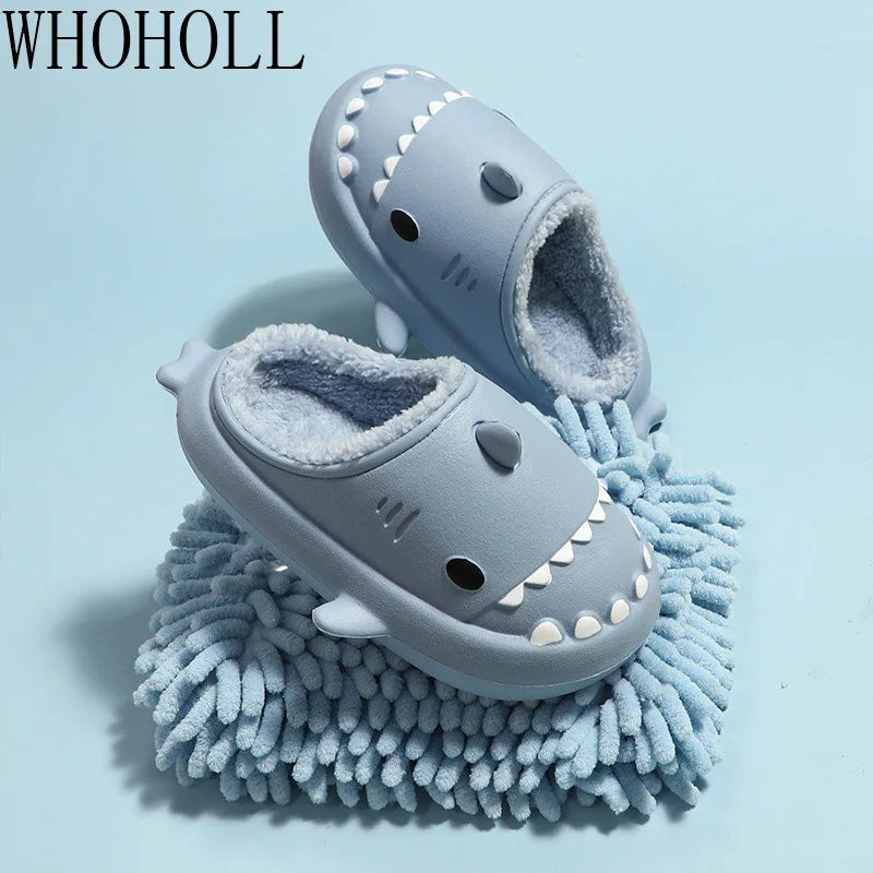 Cozy cartoon shark-shaped kids' slippers with a plush gray and blue design, featuring a fuzzy mop-like exterior for indoor comfort and warmth.