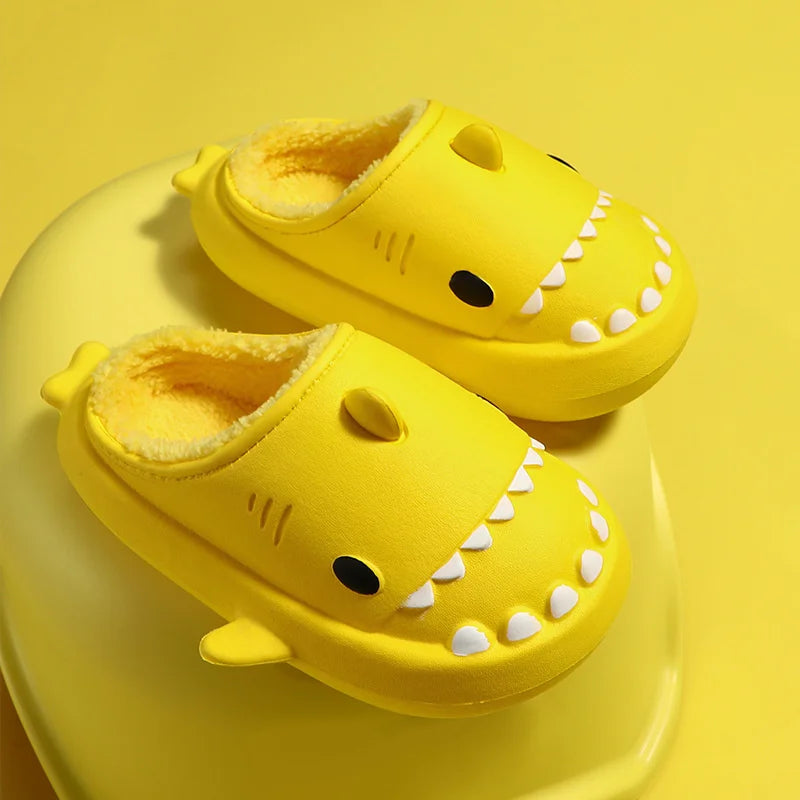 Cute yellow cartoon shark-shaped slippers with thick plush lining on white surface