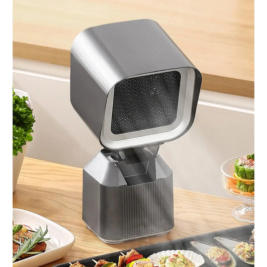 Compact kitchen range hood with sleek silver design, positioned on a wooden kitchen counter near fresh produce and prepared dishes. This portable, high-suction range hood is a practical household appliance for effective ventilation and cleanup in the kitchen.