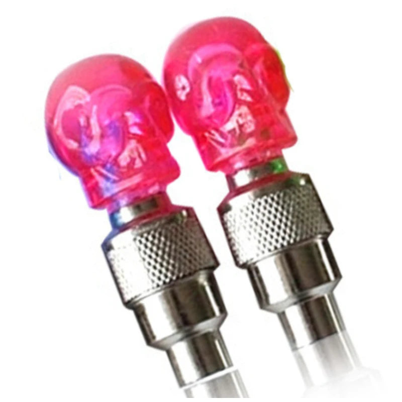 Pair of vibrant pink LED bicycle valve caps with a decorative skull design, providing a customizable lighting accent for motorcycles, bikes, and cars.