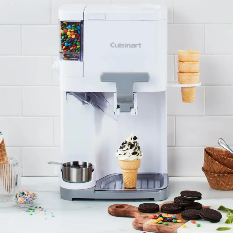 Cuisinart soft serve ice cream machine in sleek white design, with candy toppings, waffle cones, and other ice cream accessories arranged around it, showcasing its versatility for creating frozen treats at home.