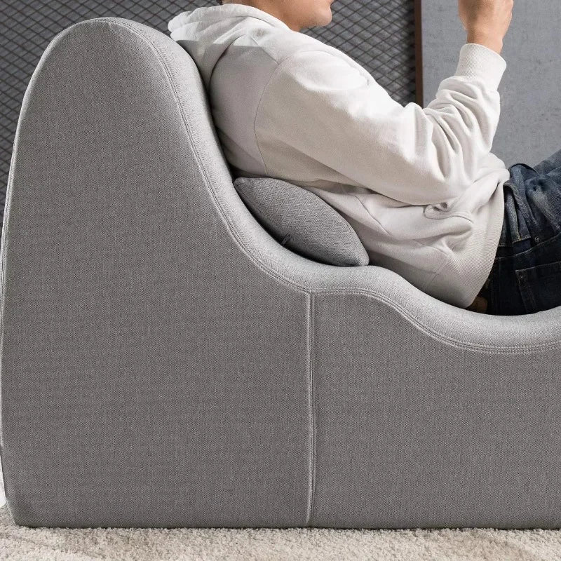 Comfortable gray chaise lounge with supportive backrest and pillow, providing ergonomic relaxation in a modern home setting.