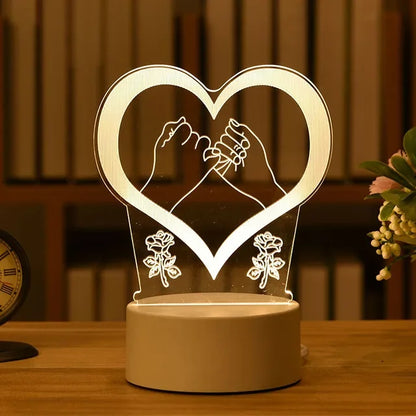 Romantic heart-shaped 3D LED lamp with intertwined arms and floral accents, creating a warm, cozy atmosphere on a wooden table with a floral decoration.