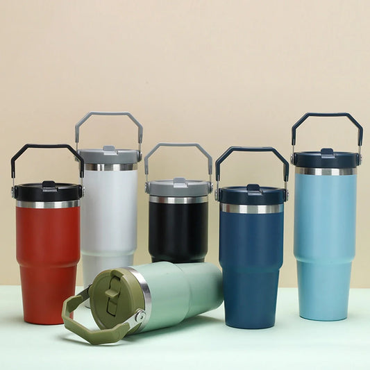 Stainless steel insulated cups in various colors including red, white, black, blue, and mint green, with handles and vacuum-sealed double-layer design for maintaining temperature.