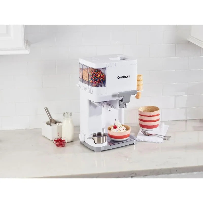 Cuisinart soft serve ice cream machine for making frozen treats like yogurt, sorbet, and gelato. Sleek white design with transparent bowl, standing on a white kitchen counter with toppings and accessories.